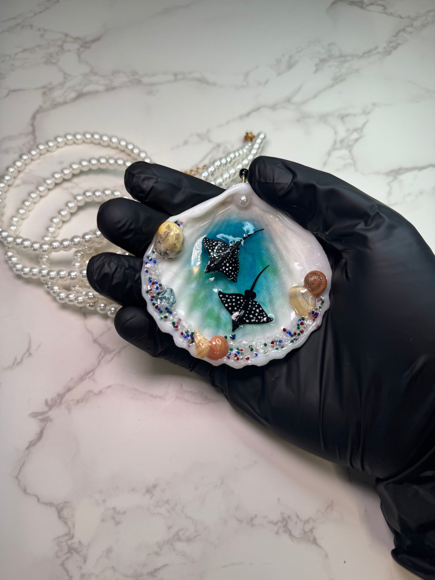 Ocean Embrace Real seashell featuring two metal handmade craft miniature manta rays and tiny natural shells, encapsulated in clear UV resin. Beautiful extra long glass pearls necklace