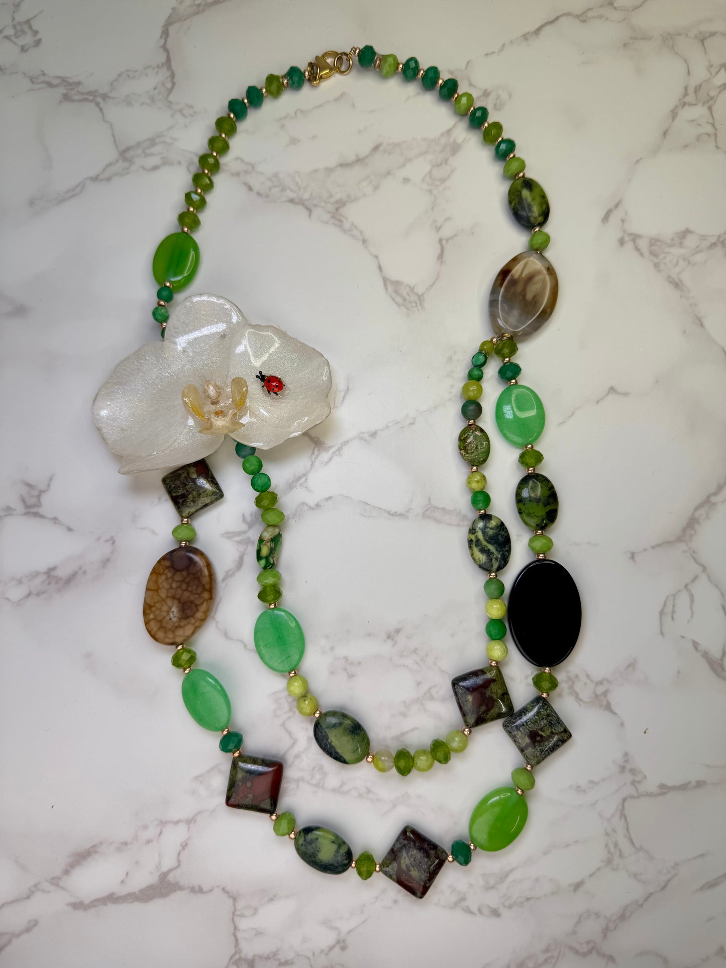 Whispering Orchid Luck White orchid flower centerpiece with a tiny red ladybug glass crystal necklace in green and beige shades