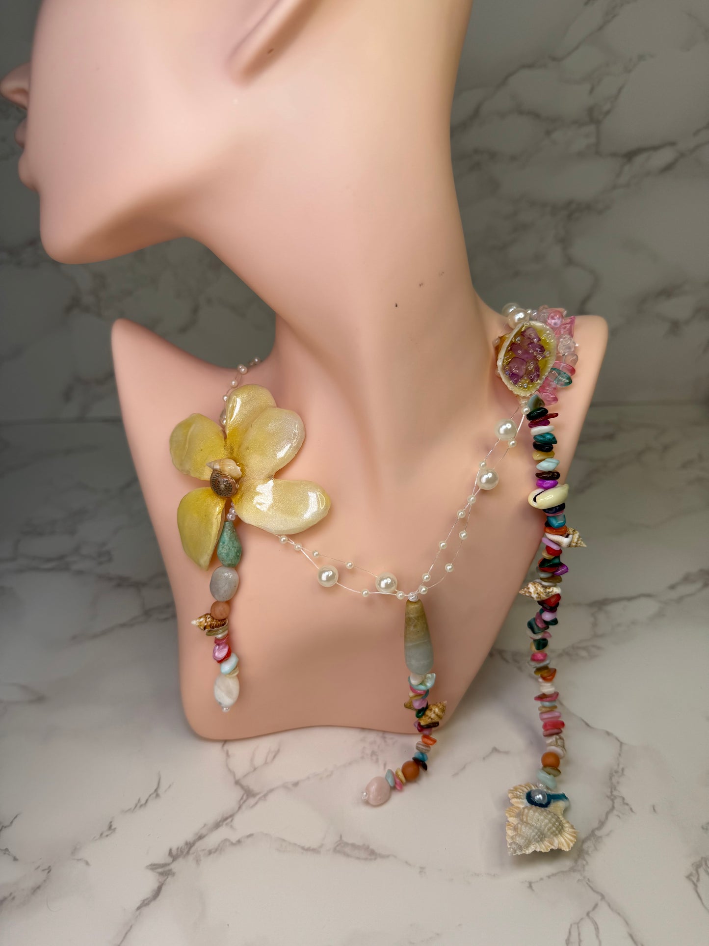 Sunbeam Carnival Bloom Yellow flower centerpiece paired with a multicolored necklace of glass rocks and shells