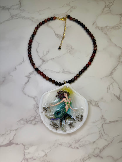 Emerald Dawn Siren  Natural seashell featuring a handmade craft metal mermaid with brown hair, yellow highlights, and a vibrant green tail preserved in Clear Resin Beautiful Stones Necklace