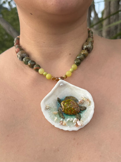 Emerald Tide Guardian Natural seashell featuring a handmade metal green sea turtle, bits of sand, coral, and a green–olive crystal ball necklace encapsulated in clear UV resin Beautiful natural stone’s necklace