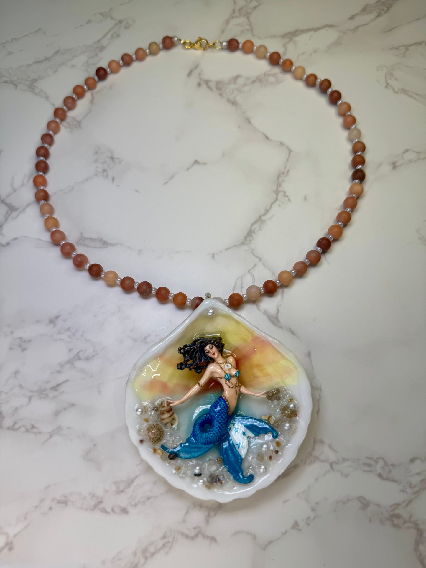 Honduras Siren Natural seashell featuring a miniature mermaid with brown hair, blue highlights, and a blue tail decorated with the Honduran flag