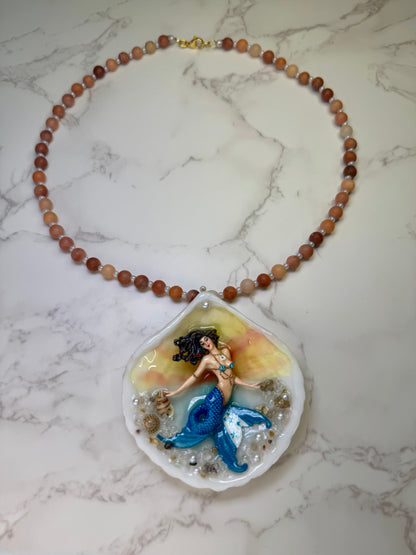Honduras Siren Natural seashell featuring a miniature mermaid with brown hair, blue highlights, and a blue tail decorated with the Honduran flag