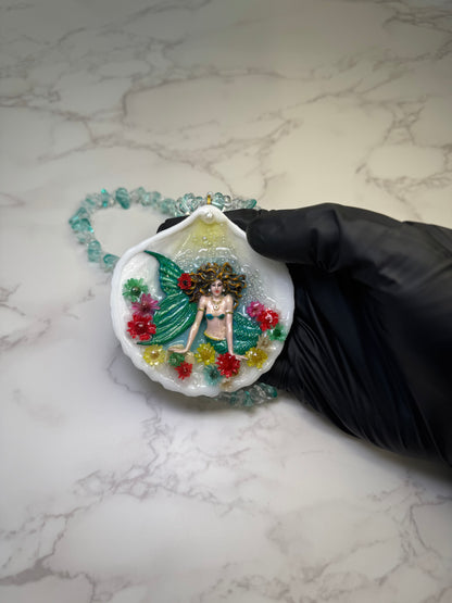 Blooming Tides Enchantress Natural seashell featuring a handmade craft metal mermaid with yellow hair and a shimmering green tail preserved in clear UV Resin. Natural Stones Necklace