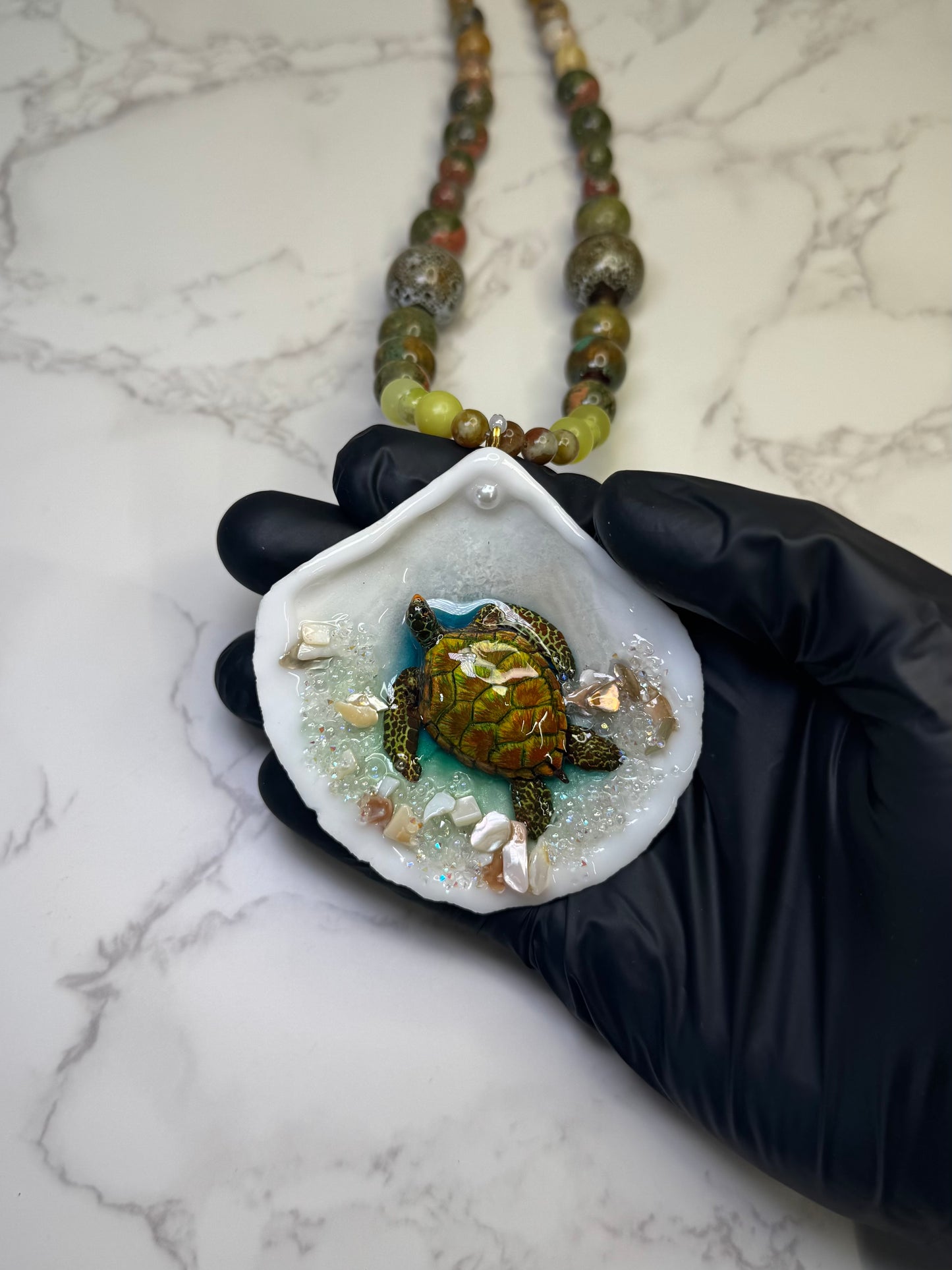 Emerald Tide Guardian Natural seashell featuring a handmade metal green sea turtle, bits of sand, coral, and a green–olive crystal ball necklace encapsulated in clear UV resin Beautiful natural stone’s necklace