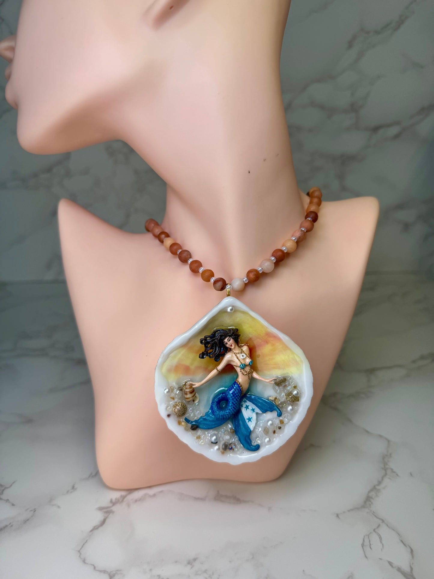 Honduras Siren Natural seashell featuring a miniature mermaid with brown hair, blue highlights, and a blue tail decorated with the Honduran flag