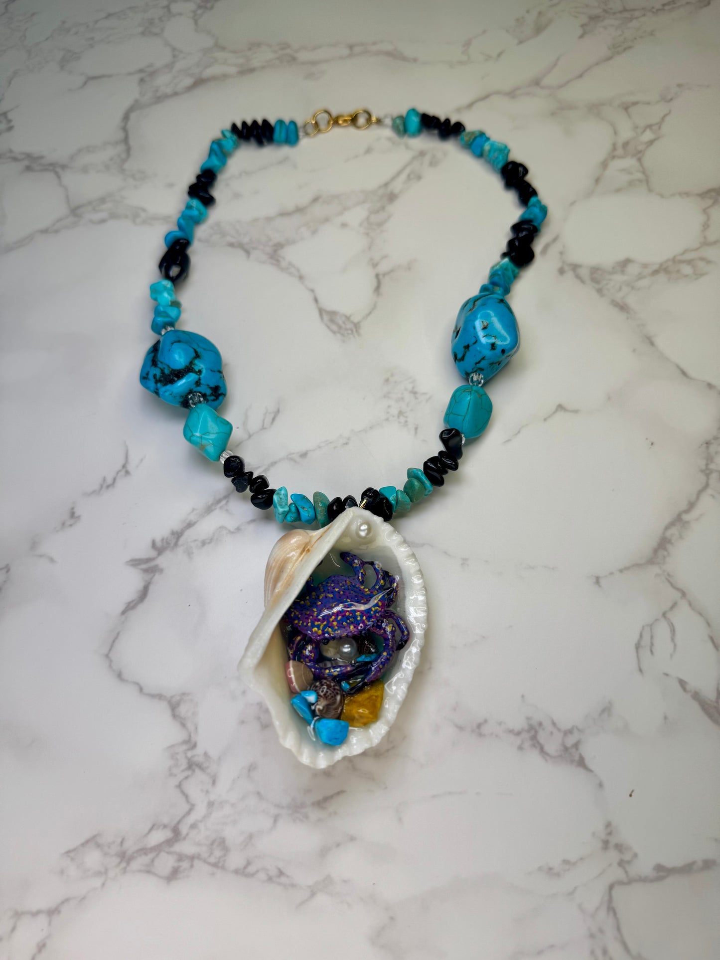 Mystic Reef Dancer Natural seashell featuring a miniature purple crab with orange and blue dots, surrounded by tiny blue rocks