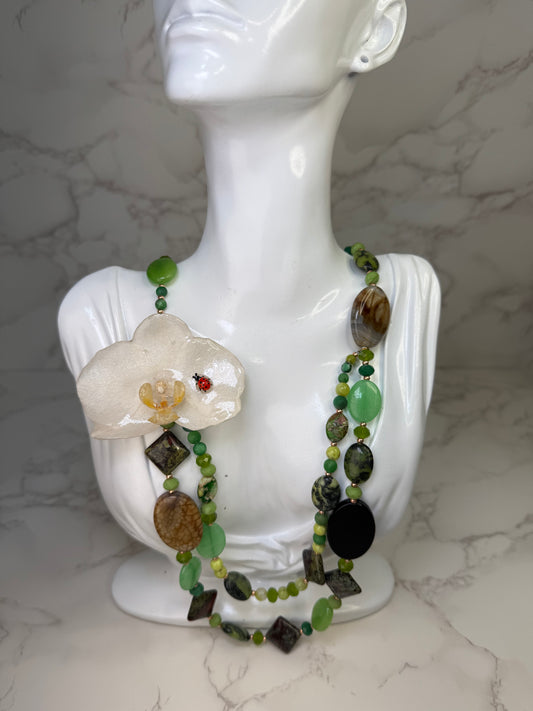 Whispering Orchid Luck White orchid flower centerpiece with a tiny red ladybug glass crystal necklace in green and beige shades