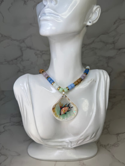 Reef Wanderer Natural seashell featuring a miniature hogfish and a beaded necklace in blue, white, green, and purple encapsulated in clear UV resin