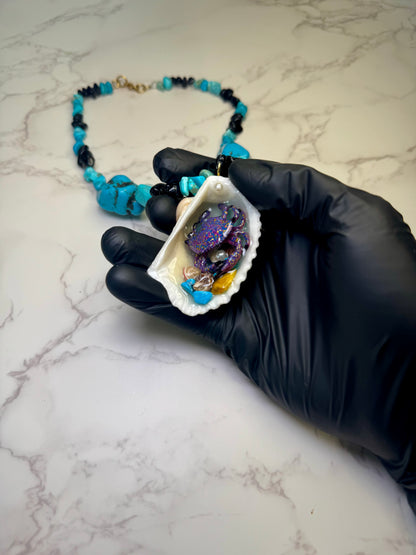Mystic Reef Dancer Natural seashell featuring a miniature purple crab with orange and blue dots, surrounded by tiny blue rocks