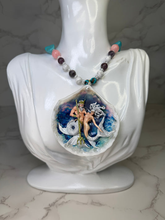 Mooncrest Royal Tides Natural seashell featuring a mermaid king holding a mermaid queen, both with white hair and white shimmering tails