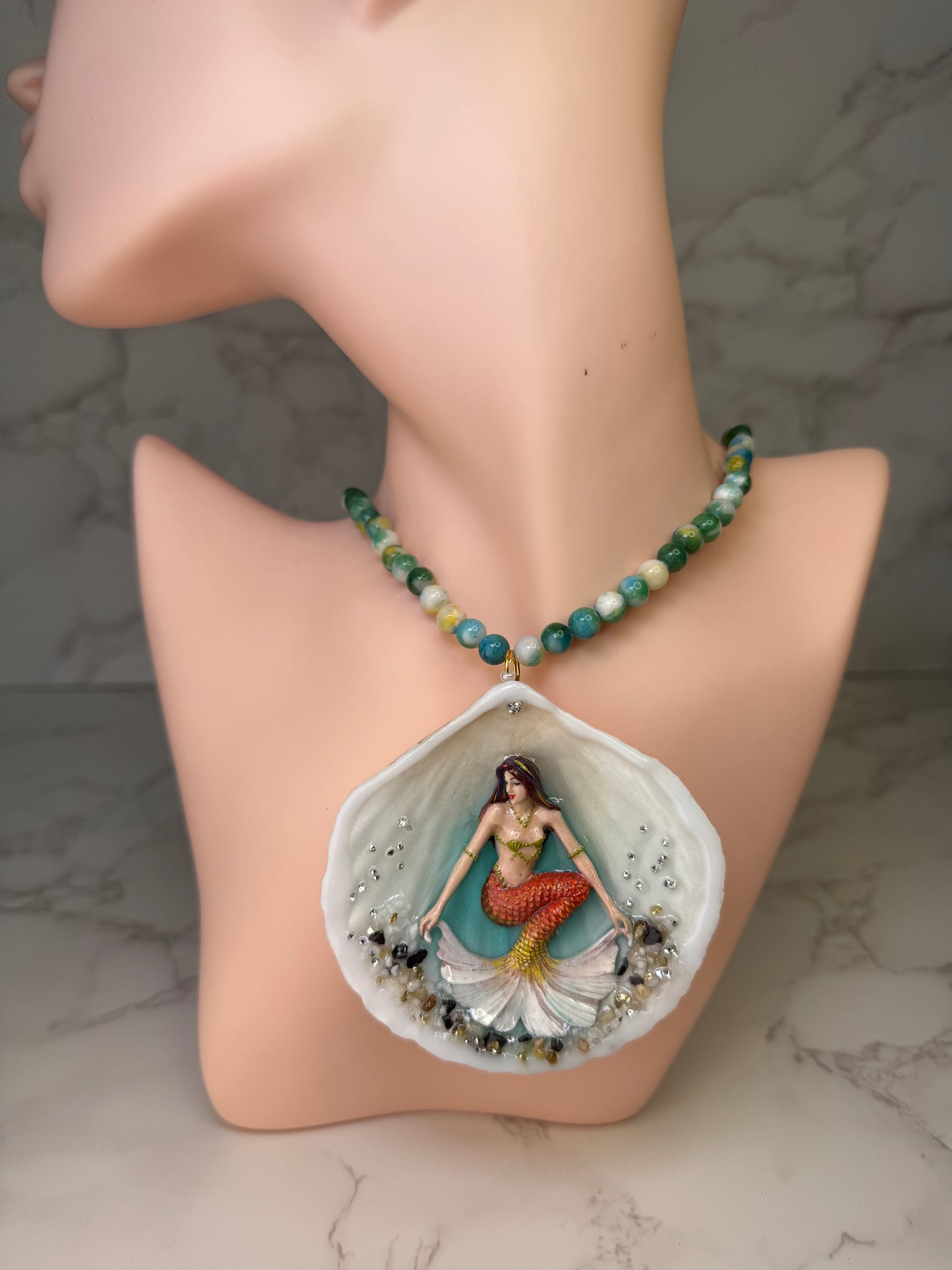 Sunlit Coral Siren Natural seashell featuring a handmade craft metal mermaid with brown hair, yellow highlights, and an orange–yellow tail encapsulated in clear UV resin Beautiful semiprecious stones necklace