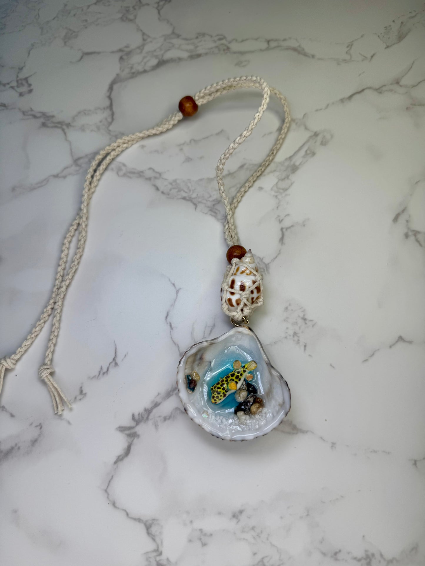 Golden Reef Keeper Natural seashell featuring a miniature yellow-and-black dotted puffer fish, tiny coral bits, and small seashells encapsulated in clear UV resin