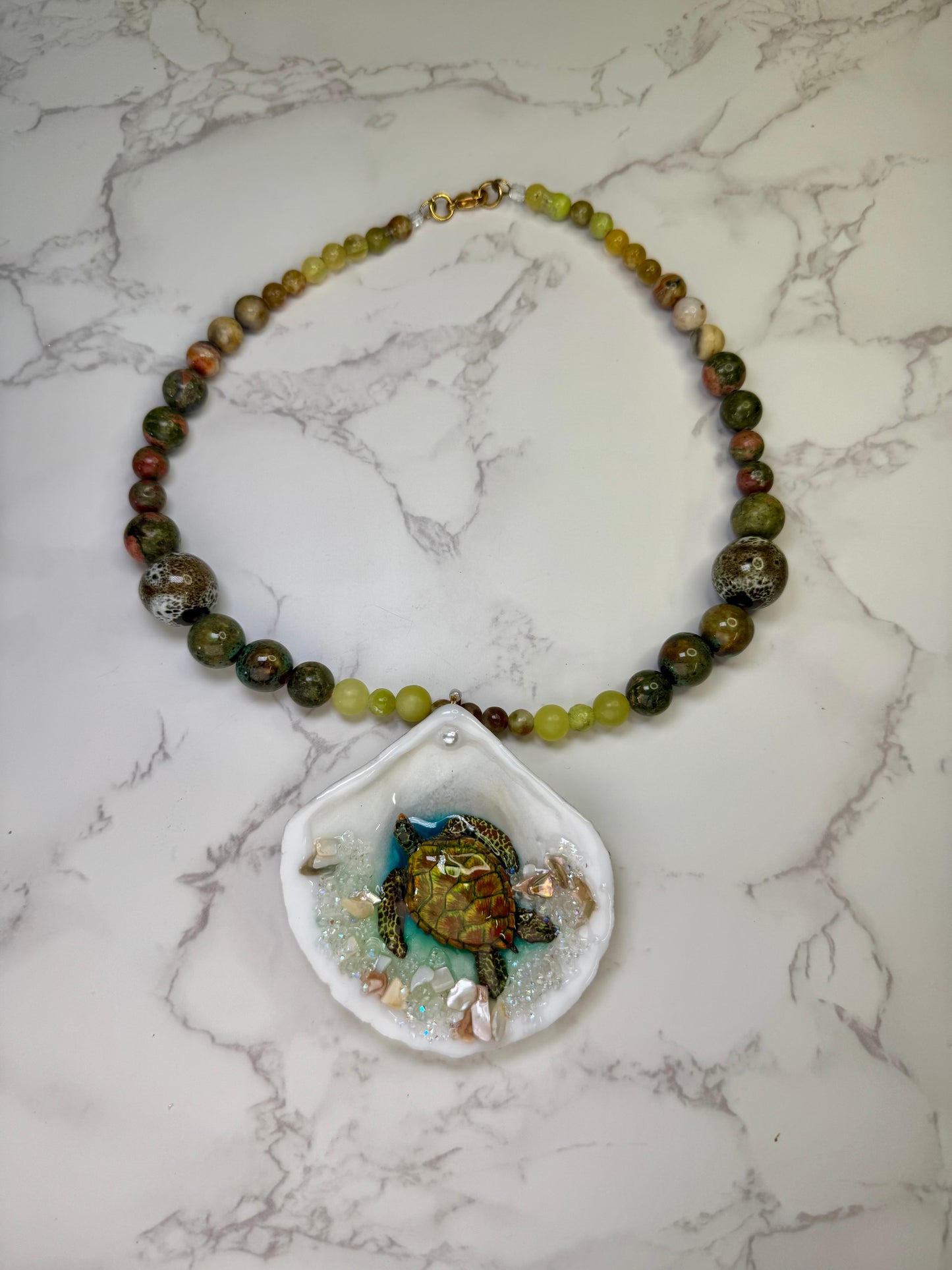 Emerald Tide Guardian Natural seashell featuring a handmade metal green sea turtle, bits of sand, coral, and a green–olive crystal ball necklace encapsulated in clear UV resin Beautiful natural stone’s necklace