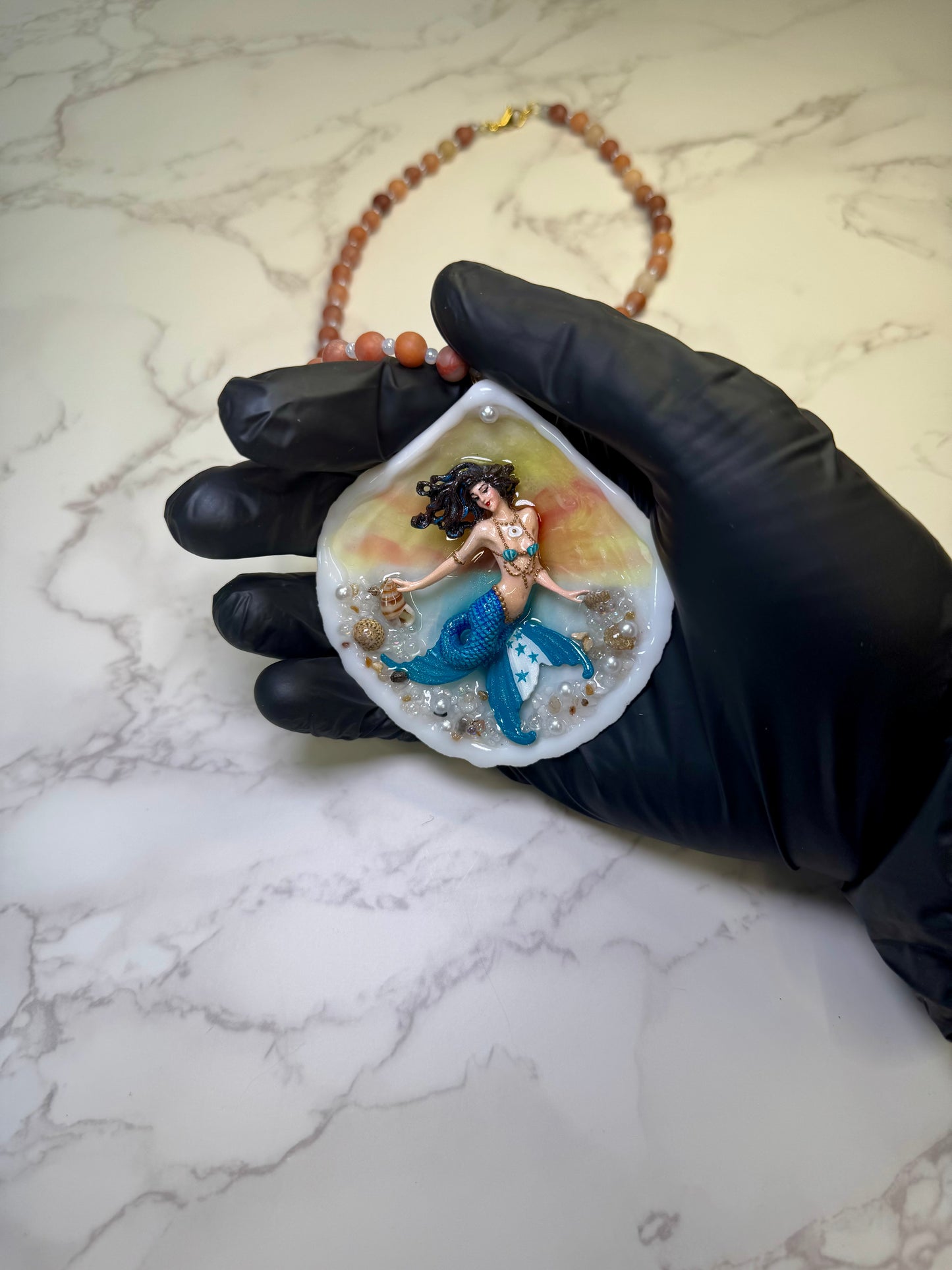 Honduras Siren Natural seashell featuring a miniature mermaid with brown hair, blue highlights, and a blue tail decorated with the Honduran flag