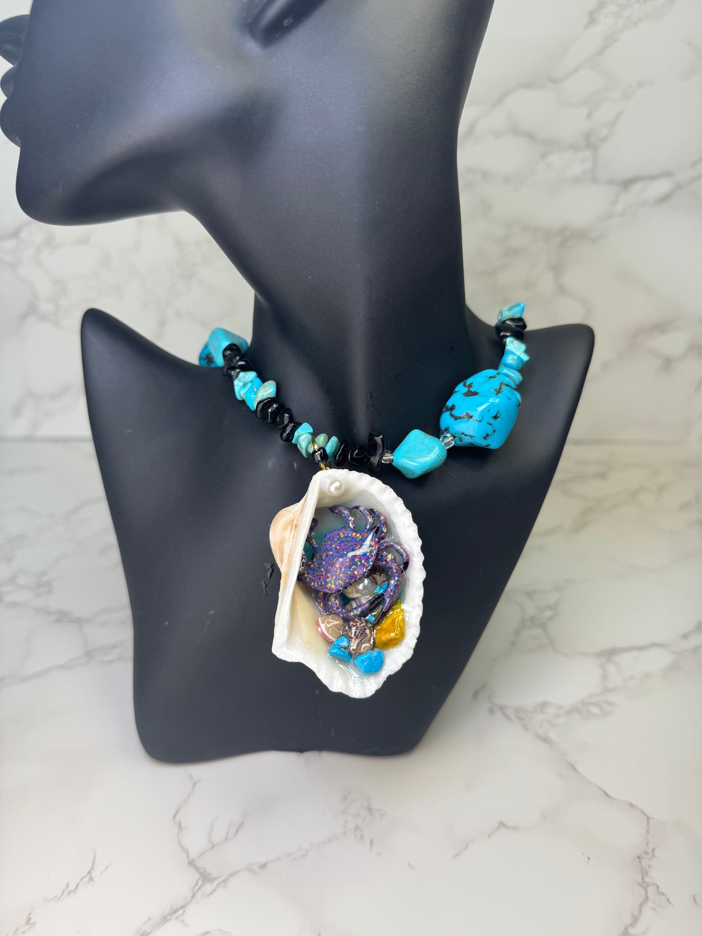 Mystic Reef Dancer Natural seashell featuring a miniature purple crab with orange and blue dots, surrounded by tiny blue rocks