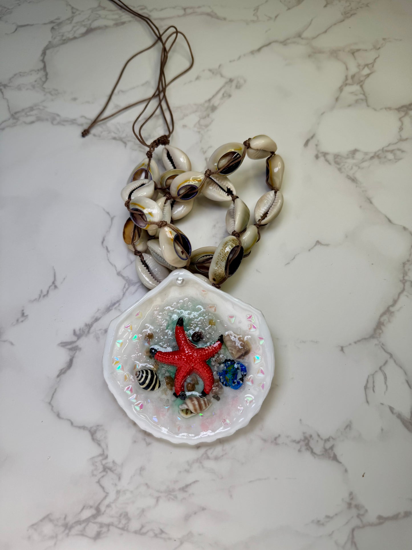 Tidebound Glow Natural seashell featuring a metal handmade craft red starfish, tiny black-and-white shells, and a swirled seashell necklace encapsulated in clear UV resin Natural shells necklace