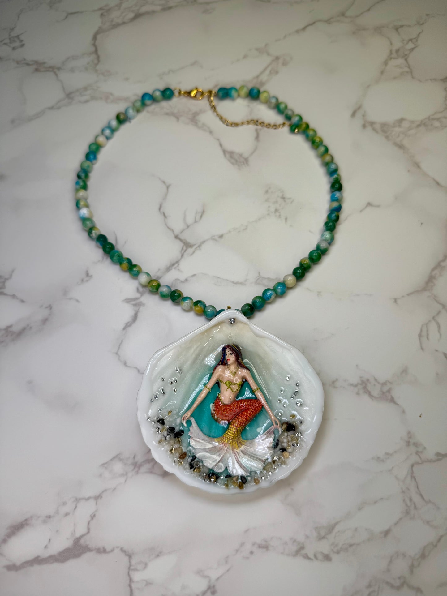 Sunlit Coral Siren Natural seashell featuring a handmade craft metal mermaid with brown hair, yellow highlights, and an orange–yellow tail encapsulated in clear UV resin Beautiful semiprecious stones necklace